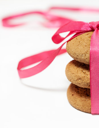 Stack three oatmeal homemade traditional tasty cookies with pink ribbon and bow as gift macro verticalの写真素材