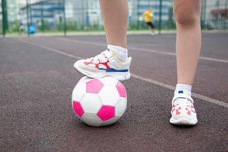 Young girl soccer player with a pink soccer ball isolated on a soccer field or brown backgroundのeditorial素材