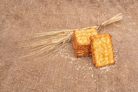 A cracker or cookie with sesame seeds on a burlap or jute cloth.の写真素材