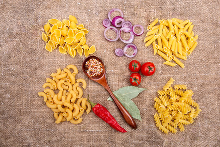 Raw Pasta with ingredients on linen or jute sacking or fabric.