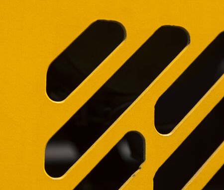 Ventilation slits for cooling the engine in the body of yellow road machinery close-upの写真素材