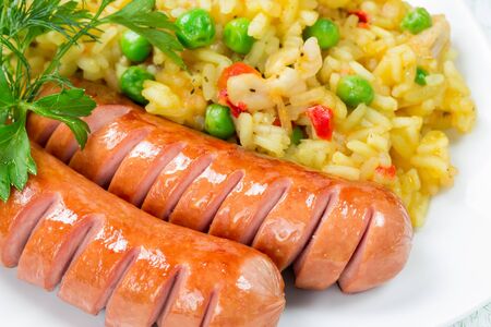 Rice with vegetables and greens and two sausagesの写真素材