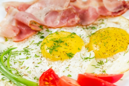 Fried eggs with bacon, greens and tomatoesの写真素材