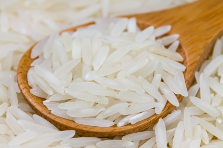 Uncooked long grain rice in a wooden spoonの写真素材