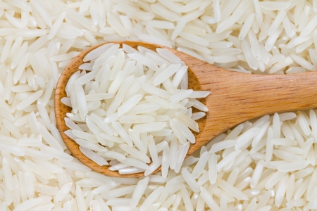 Uncooked long grain rice in a wooden spoonの写真素材