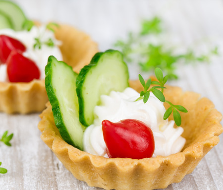 Tartlers with cream, pepper and cucumber on a wooden backgroundの写真素材