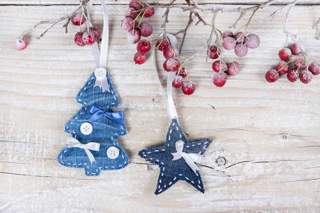 Christmas trees and stars on a branch with berries on wooden backgroundの写真素材