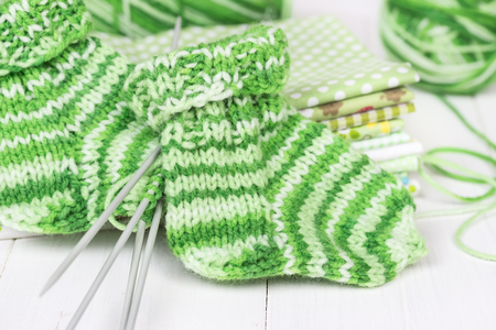 Baby knitting socks on a white wooden backgroundの写真素材