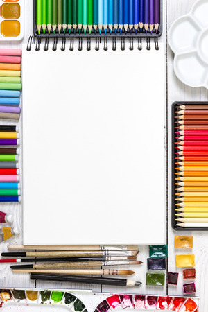 Artist workspace on white wooden background: watercolor, sketchbook, brushes pencils and markers. Top view. Mock up. の写真素材