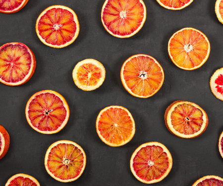 Red bloody oranges on black stone background.