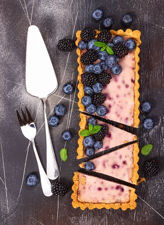 Cheesecake with fresh blackberries, blueberries and mint on a gray stone background.の写真素材