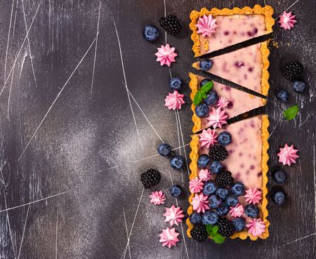 Cheesecake with fresh blackberries, blueberries, meringue and mint on a gray stone background.の写真素材