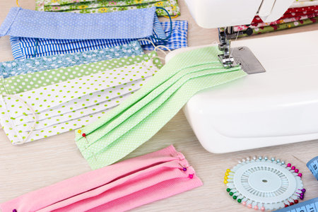 Sewing reusable fabric masks at home for coronavirus protection. Handmade multicolored fabric face...