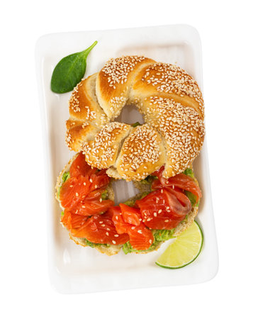 Sliced salmon with avocado on bagel with sesame seeds isolated on white background. Top view....