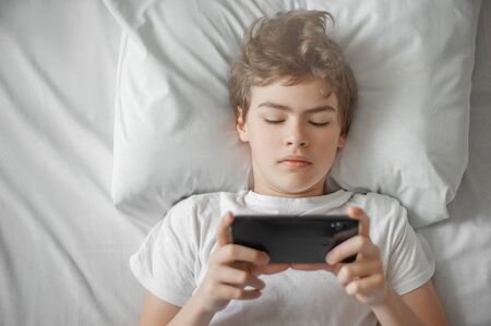 The teenager sleeps in bed. He fell asleep with the book.の写真素材