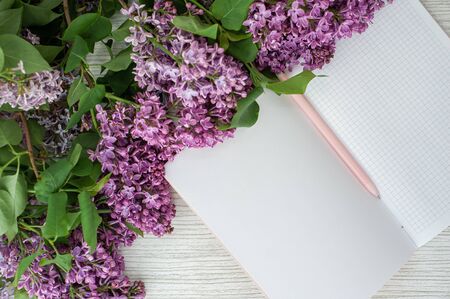 Lilac on a wooden table. An open notebook and a pen.の写真素材
