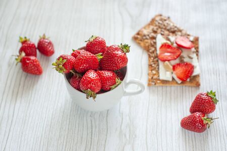 On a light wooden background of strawberries in a cup and cookies with seeds, cream cheese, kesy and sliced strawberries.の写真素材
