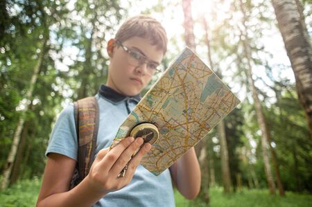 A boy with a map and a compass in the woods.の写真素材