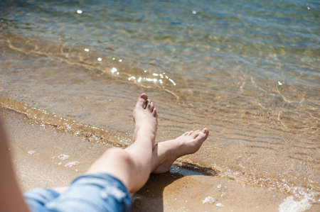 Legs on the surf line. Rest by the water.の写真素材