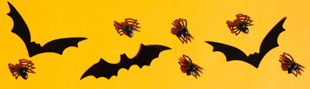 Banner for Halloween. Black spiders and bats on an orange background.