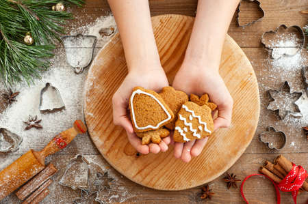 The process of cooking Christmas gingerbread. The boy cuts the gingerbread out of the dough. Christmas cooking on a brown wooden background.の写真素材