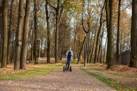 A boy  rides through the autumn park alone.の写真素材