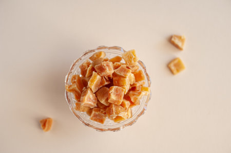 Pumpkin candied. Unusual healthy sweets. Pieces of dried pumpkin in a glass plate on a beige background.の写真素材