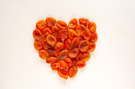 Dried apricots laid out in the shape of a heart on a beige background. Valentines Day. Healthy sweets. Food for heart health. Vegan food.の写真素材