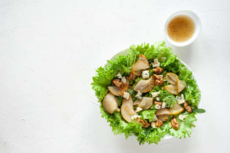 Vitamin Diet lightweight salad with pear and blue cheese in an oval plate on a white table. Copy space Top viewの写真素材