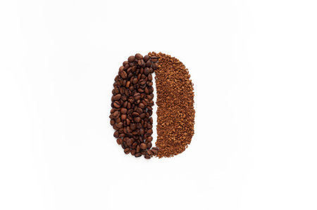 Roasted coffee beans and instant granulated coffee laid out in the form of a large coffee grain on a...