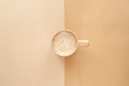 Hot cappuccino with milk foam in a beige cup on a beige background. View from above, Place for text. Monochrome and minimalism.の写真素材