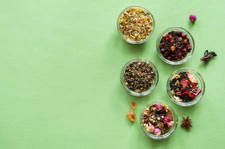 A set of different types of green, black and herbal tea on a green background. Delicious organic drinks. View from above. A place for text.の写真素材
