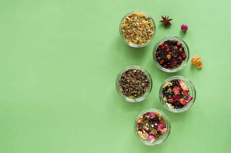 A set of different types of green, black and herbal tea on a green background. Delicious organic...