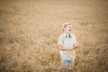 A boy blond Caucasian laughs and has fun in a wheat field. Copy spaceの写真素材
