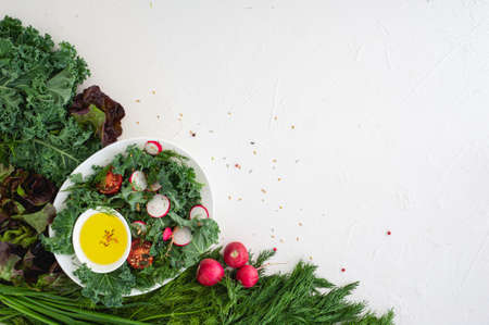 Kale cabbage salad, herbs, tomatoes and radishes in a white oval plate on a white background. Vegan food. Healthy eating. Diet lunch. Copy space.の写真素材