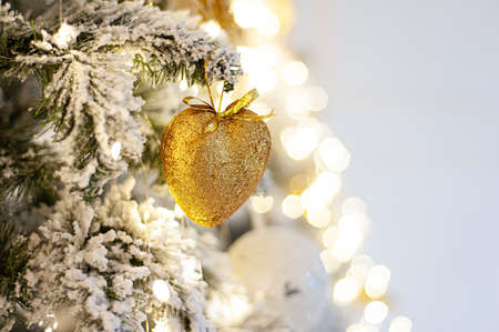 Decorated Christmas tree with a heart of gold. A branch of a snow-covered tree with Christmas decor with a soft focus. Copy space. Place for textの写真素材