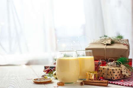 Two glasses of eggnog on a white wooden table next to the Christmas presents. Sweet egg dessert. Christmas breakfast.の写真素材