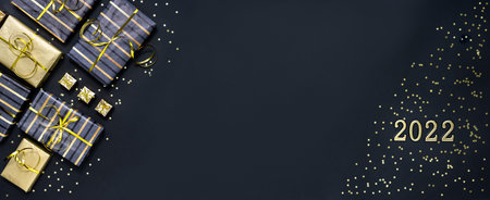 Boxes with Christmas gifts in gray and gold color on a dark background with the numbers 2022. New...