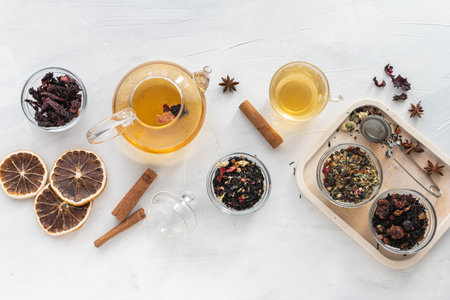 A set of different varieties of Chinese herbal and green tea in a glass dish and a kettle with hot...