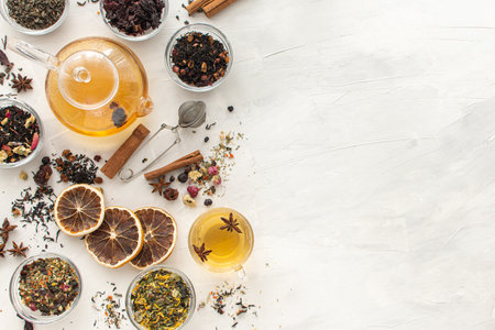 Several varieties of herbal and fruit tea in glass bowls and a kettle with a cup of hot tea on a light background. View from above. Healthy eating. Delicious warming drink. Copy spaseの写真素材