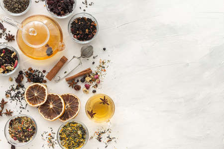 A set of different varieties of Chinese herbal and green tea in a glass dish and a kettle with hot tea on a green background. View from above. Space for text. Herbal treatment. Healthy lifestyle.の写真素材