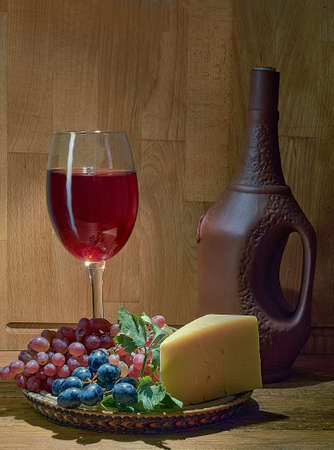 Glass of wine, grapes and cheese on a plateの写真素材