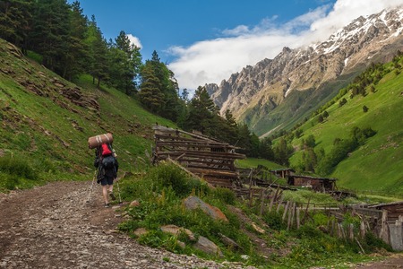 Tourist with backpack goes up gorge of Caucasus Mountainsの写真素材