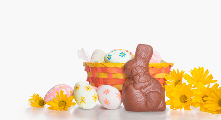 Easter basket with flowers, eggs and cute bunny isolated on white background