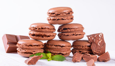 Macaroons with Sweet Chocolate and Coffee Beans on White Wooden Tableの写真素材