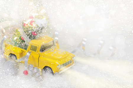 Yellow Car Carrying Decorated Christmas Tree on White Snowy Background.の写真素材