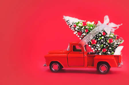 Red Car Carrying Christmas Tree on a Red Background. Christmas Backgroundの写真素材