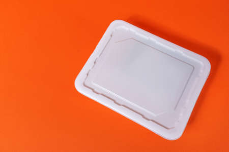 Lid of a white plastic box fast food on an orange background - top view, isolateの写真素材