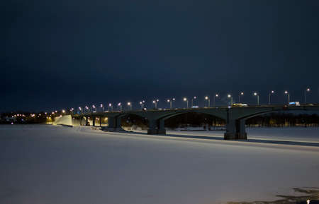Night view of the bridge with lights over the river covered with ice, winter cityscapeの写真素材
