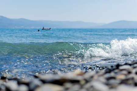 Sea wave beats on the shore, wet stones on the sea shore, mountains on the horizon
